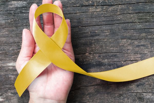 Symbolbild: Eine Hand hält eine gelbes Schleife als Zeichen für Suizidprävention
