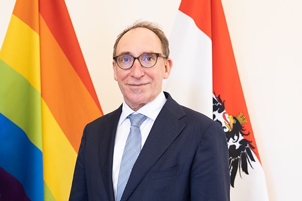 Portraitfoto HBM Johannes Rauch vor Pride- und Österreich-Flaggen
