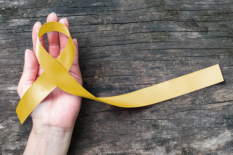 Yellow ribbon symbolic color for Sarcoma Bone cancer, Spina Bifida Awareness Month and suicide prevention on helping hand (isolated with clipping path)